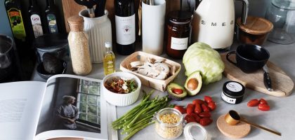 Various colorful healthy food and vegetables locating on countertop next to many different utensils and white kettle during cooking in stylish kitchen